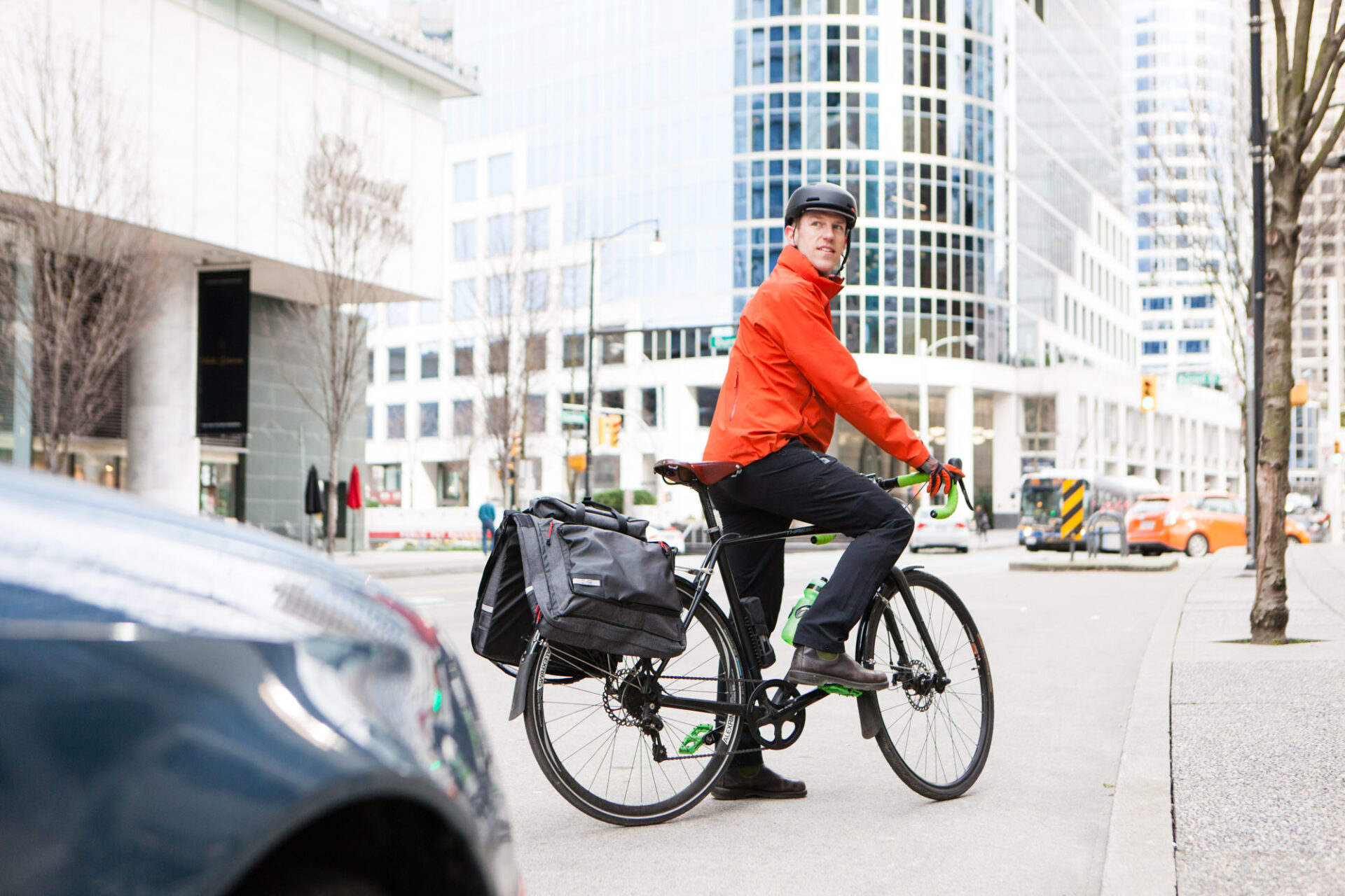 A man on his bicycle does a shoulder check in traffic in downtown Vancouver.
